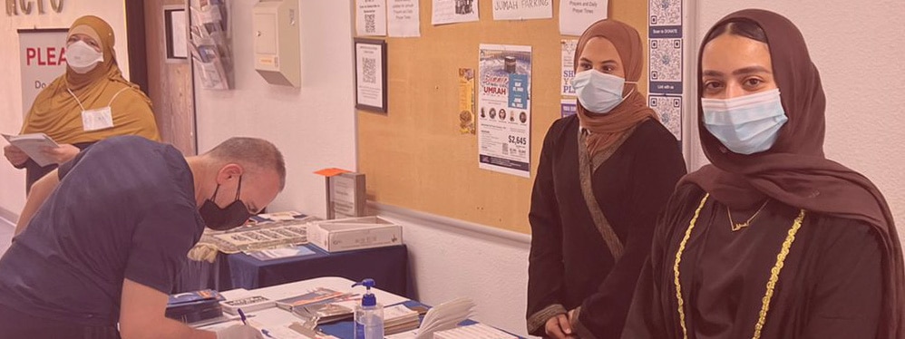 Two women wearing hijabs stand behind a medical information booth