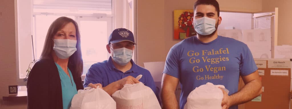 Three restaurant workers hold donated meals they've prepared