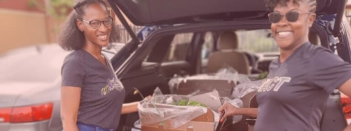 Two black woman load fresh produce into the trunk of a car